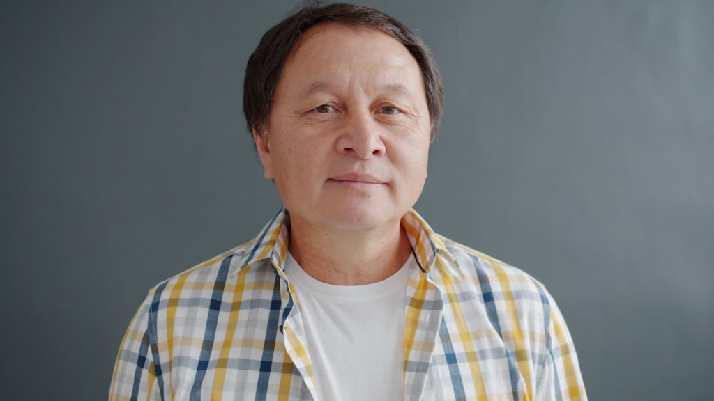 一位身穿格紋衣的東方長者男性,神情平靜,象徵告別前父親自己錄製旁白的時刻