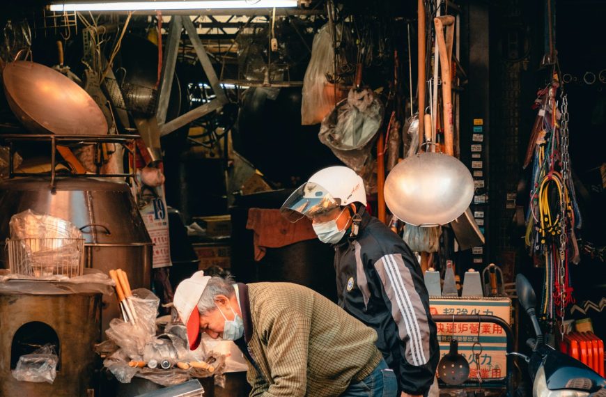 台灣傳統市場的鐵店招牌與兩位戴口罩工作的東方男性,象徵阿公賣魚五十年的攤位