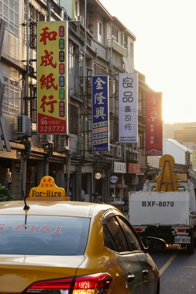 一輛台灣黃色計程車停在街上,背景是和成紙行、金隆興等中文招牌,象徵父親開計程車四十年的台北街景